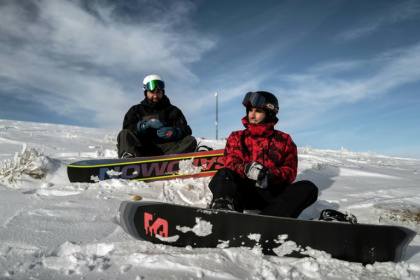 Les réfugiés afghans et snowboarders Musawer (d) et Nizar (g) se préparent à une descente à Viuz-la-Chiesaz, près de la station du Semnoz, dans le massif des Bauges, le 29 janvier 2025 en Haute-Savoie