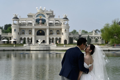 Un couple de mariés pose pour des photos au parc Chaoyang à Pékin, le 21 juillet 2024