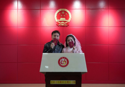 Les jeunes mariés Xue Zhenkai (g) et Liu Cuifang montrent leur livret de mariage dans un bureau de Lüliang, dans la province du Shanxi, dans le nord de la Chine, le 12 février 2025