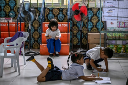 Des élèves en pleine activité sous des ventilateurs dans une école primaire sur l'île de Baseco, à Manille, le 21 mars 2025