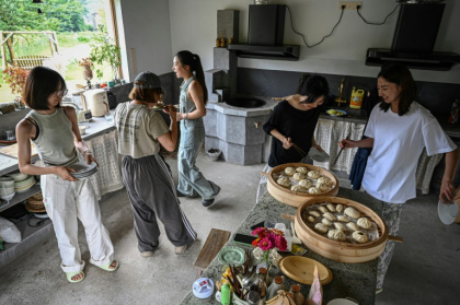 Chen Yani (d), fondatrice du lieu "L'Univers imaginaire de Keke", déjeune avec des participantes dans la cuisine du gîte rural, le 14 juillet 2025 à Hangzhou, dans la province du Zhejiang, dans l'est de la Chine - Jade GAO (AFP) Chen Yani (d), fondatrice du lieu "L'Univers imaginaire de Keke", déjeune avec des participantes dans la cuisine du gîte rural, le 14 juillet 2025 à Hangzhou, dans la province du Zhejiang, dans l'est de la Chine - Jade GAO (AFP)