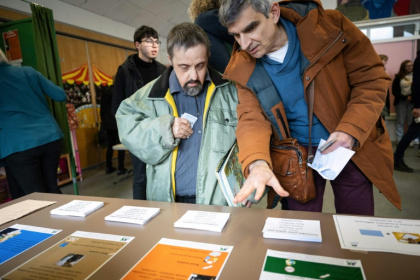 Un éducateur explique les règles pour voter lors d'un faux scrutin organisé pour des personnes en situation de handicap intellectuel, le 17 février 2026 à  Saint-Dié-des-Vosges - SEBASTIEN BOZON (AFP)