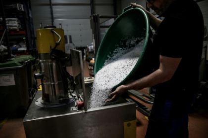 Un employé de l'usine Francia, spécialisée dans l'injection de plastique, déverse des granulés de plastique dans une machine, le 16 avril 2026 à Bellignat, dans l'Ain - JEFF PACHOUD (AFP)