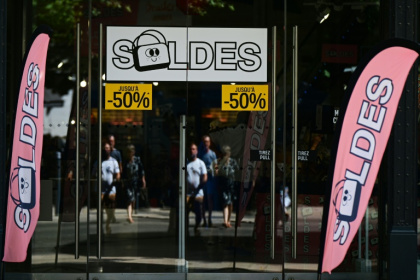 Des passants se tiennent devant la vitrine d'un magasin annonçant des réductions à l'occasion des soldes d'été, à Béziers, dans l'Hérault, le 28 juin 2025 - Emma DA SILVA (AFP)
