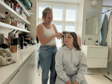 Nora Pihl, une Danoise de 15 ans, se fait coiffer par sa mère, Anne Pihl, le 23 mai 2026 à Copenhague, avant sa confirmation - Camille BAS-WOHLERT (AFP)