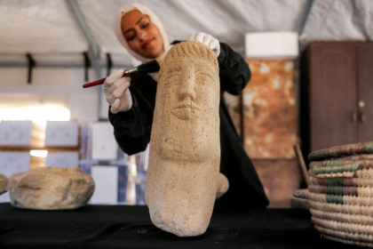 Une membre de l'association Mayasem pour la culture et les arts nettoie un artefact à la brosse, sous une tente à Khan Younès, dans le sud de la bande de Gaza, le 11 juillet 2026 - Bashar Taleb (AFP)