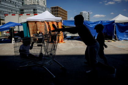 Des enfants jouent près de tentes installées sur le parvis du siège du Samusocial, occupé par des familles et des personnes en attente d'un hébergement d'urgence, à Paris, le 1er août 2026 - Simon WOHLFAHRT (AFP)